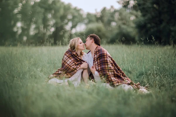 Manželský pár, líbání, seděli pod teplou deku na trávníku — Stock fotografie