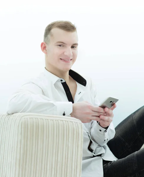 Улыбающийся мужчина со смартфоном сидит на диване в своей гостиной — стоковое фото