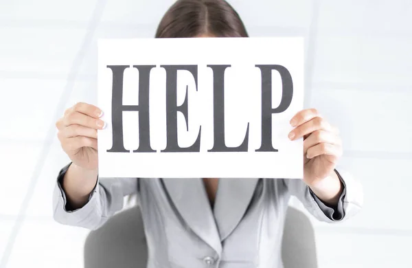 Business woman holding a sign saying help ,sitting behind a Desk — Stock Photo, Image