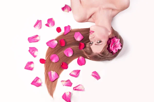 Schöne Mädchen Ruhebereich, zwischen Rosenblättern liegend — Stockfoto
