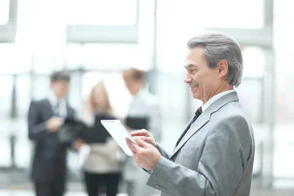 Close up.Mature businessman with digital tablet on blurred office background — Stock Photo, Image