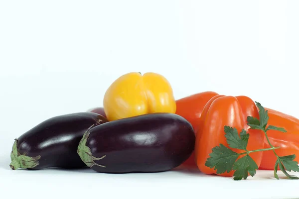 Paprika, aubergines en takjes peterselie op een witte achtergrond. — Stockfoto