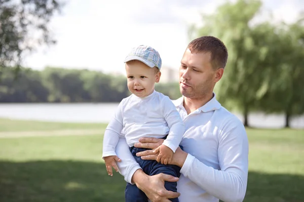 Feliz padre con su pequeño hijo de pie en un Sunny Park . —  Fotos de Stock