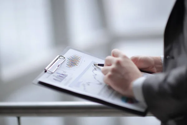 Close up.businessman checking sales schedule.photo on blurred background — Stock Photo, Image