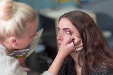 makyaj sanatçısı genç bir kadın müşteri için makyaj yapıyor