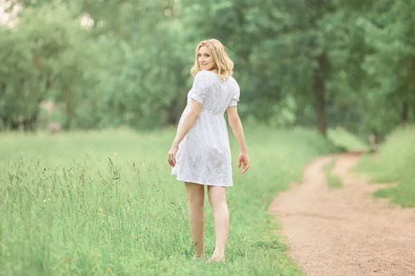 Bakifrån. gravid kvinna gå barfota på gräs. — Stockfoto