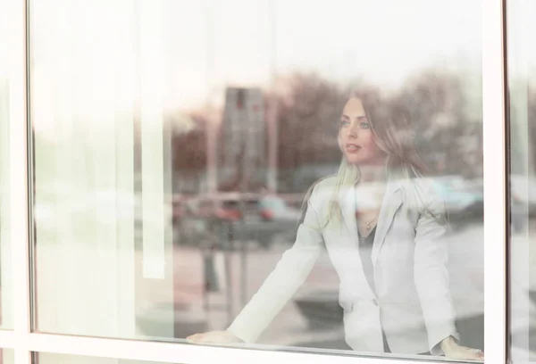 Mulher de negócios bem sucedida olha para fora da janela de seu escritório — Fotografia de Stock