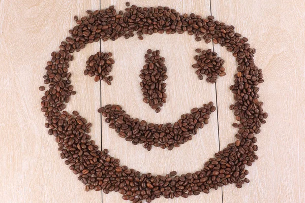 Lustiges Gesicht schwarzer Kaffeebohnen auf hölzernem Hintergrund — Stockfoto