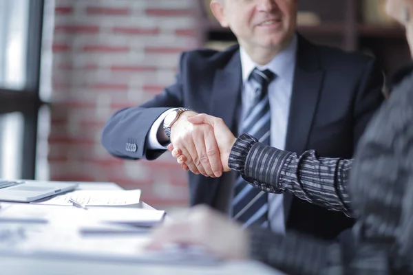 Handshake parceiros de negócios perto da área de trabalho no escritório . — Fotografia de Stock