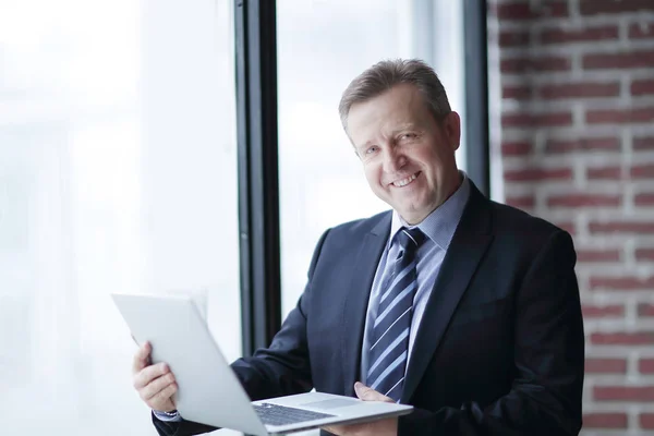 Självsäker affärsman med laptop stående i office. — Stockfoto