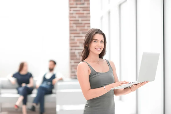 Joven mujer de negocios con portátil de pie cerca de la ventana de la oficina — Foto de Stock