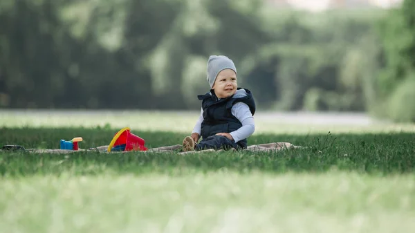 Menino sentado no gramado em um dia de primavera — Fotografia de Stock