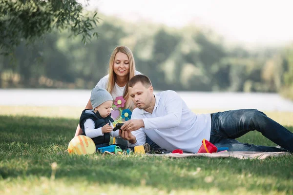 Родители играют со своим маленьким сыном, сидящим на траве — стоковое фото