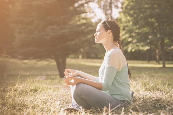 Lado view.young mujer meditando en posición de loto al aire libre —  Fotos de Stock