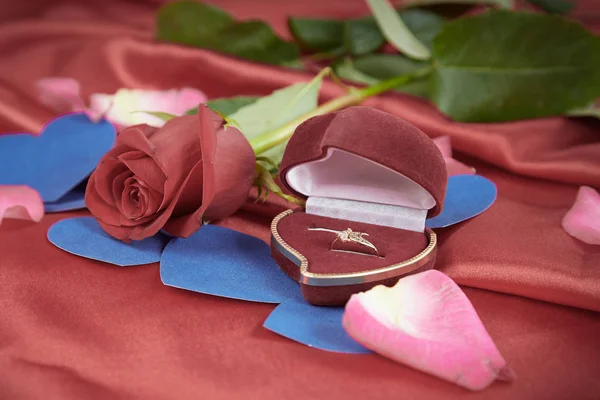 Diamentowy pierścień i róża na jasnym czerwonym tle — Zdjęcie stockowe