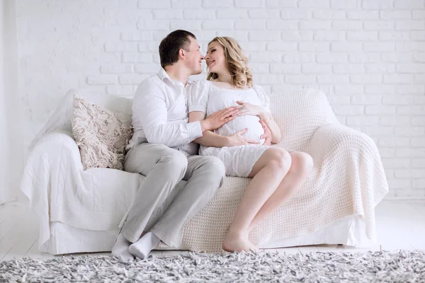 Junge zukünftige Eltern sitzen auf der Couch im Wohnzimmer. — Stockfoto