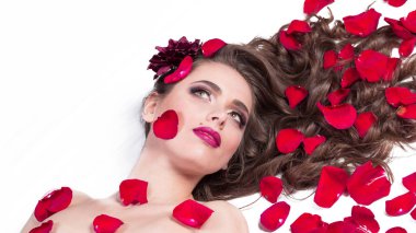 güzel genç kadın gül yaprakları arasında yatıyor