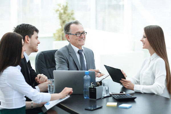 Менеджер обсуждает рабочие вопросы со своими помощниками за столом
