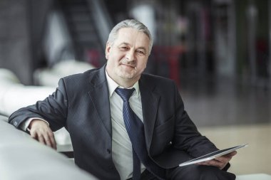 ofis önünde sandalyede oturan dijital tablet ile işadamı portresi.