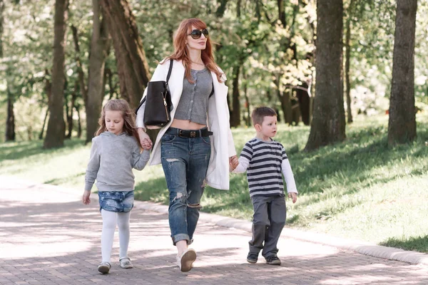Mama z dwoma dziećmi chodzenie w parku miejskim — Zdjęcie stockowe