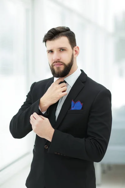 Portrait of confident businessman adjusting his tie — Stock Photo, Image