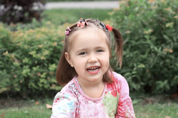 Happy Little Girl zittend op het gazon op een zomerdag — Stockfoto