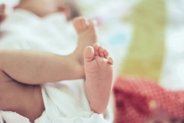 Close-up van de benen van een pasgeboren baby liggend op een deken in de wieg — Stockfoto