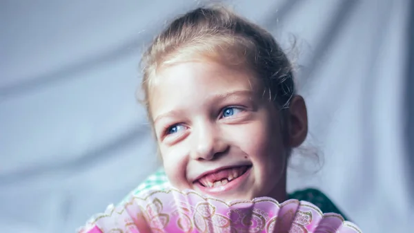 Smiling little girl with a fan in the nursery — Stock Photo, Image