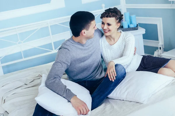 Joven pareja feliz sentado en la cama en el amplio dormitorio . — Foto de Stock