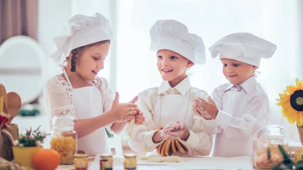 Счастливые маленькие дети в форме шеф-повара, чтобы приготовить вкусное — стоковое фото