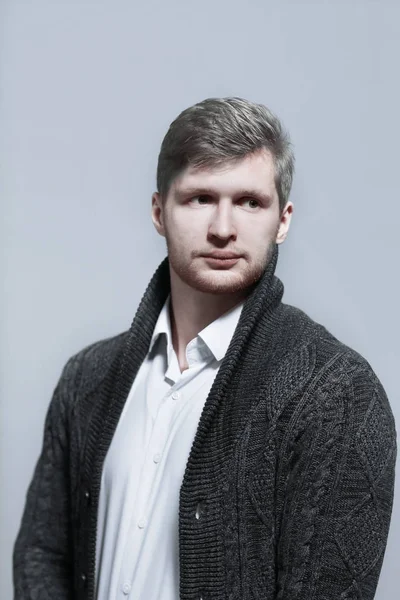Elegante giovane uomo in un cardigan.isolated maglia su sfondo grigio — Foto Stock