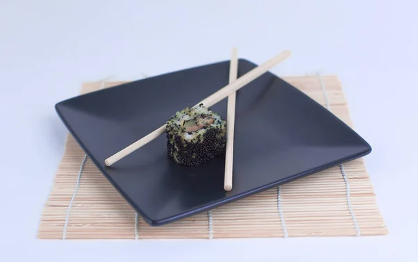 Gros plan des sushis et des baguettes sur une assiette noire — Photo