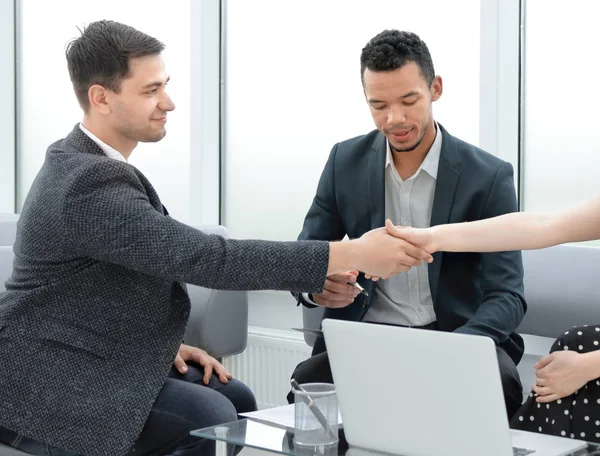 young business partners shaking hands at a business meeting