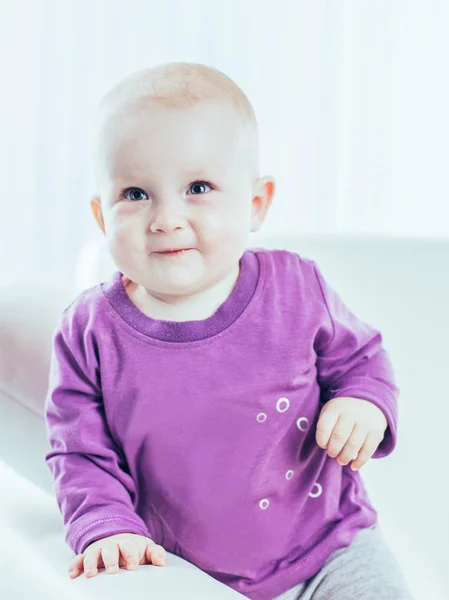 portrait of a happy one year old baby girl on a background of bright childrens room