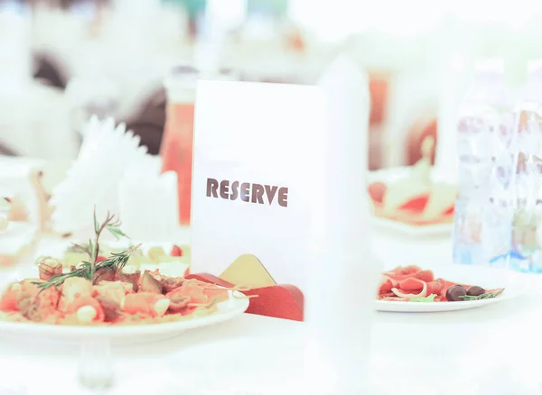 Sinal reservado em uma mesa de restaurante, em meio a deliciosos pratos — Fotografia de Stock