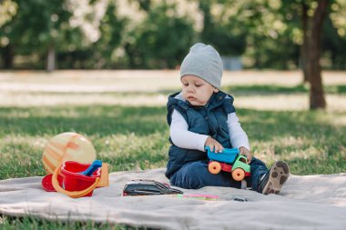 çok güzel bir çocuk çimenlerin üzerine oturmuş bir oyuncak araba ile oynarken