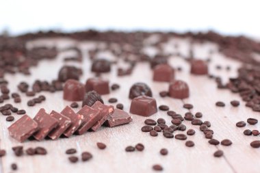 siyah kahve çekirdekleri ve ahşap arka plan üzerinde çikolatalar