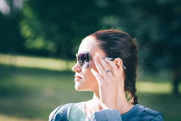 Elegantní mladá žena v sluneční brýle někde při pohledu na stranu — Stock fotografie