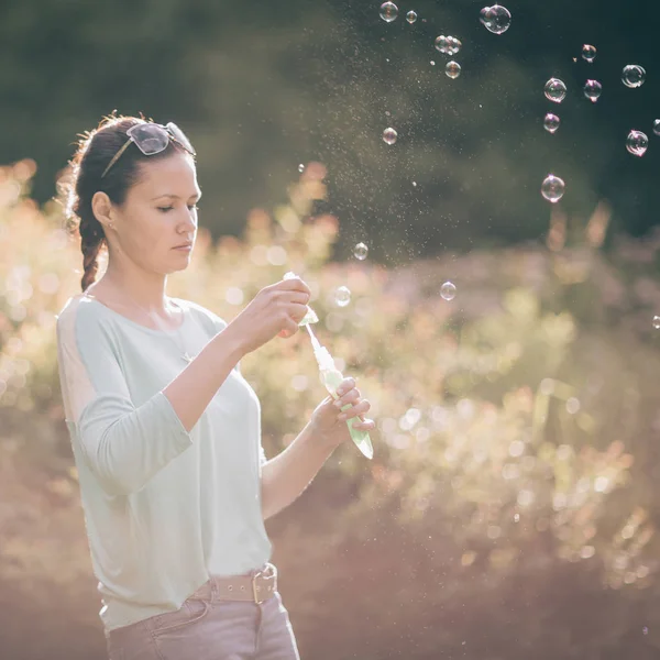 Beautiful young woman playing with soap bubbles in Sunny Park. — Stock Photo, Image