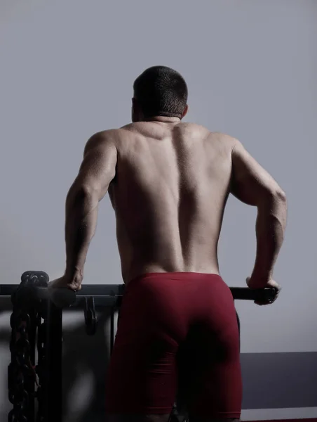Stylischer männlicher Bodybuilder, der Übungen im Simulator durchführt. — Stockfoto