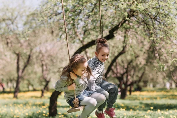 mom and her two pretty daughters on a swing