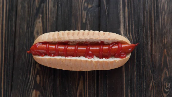 Hot dog s klobásou na tmavé dřevěné background.photo s kopií prostor — Stock fotografie