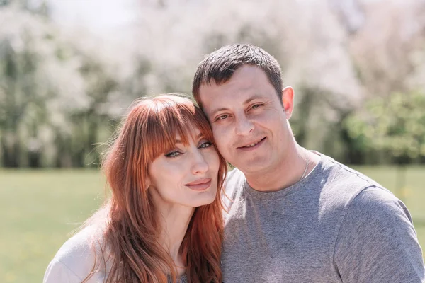 Jovem casal apaixonado de pé em um parque de primavera — Fotografia de Stock