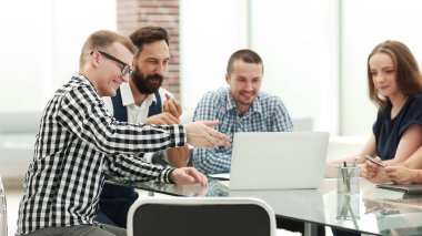 iş ekibi laptop ekranına bakıyor ve fikirlerini tartışıyor