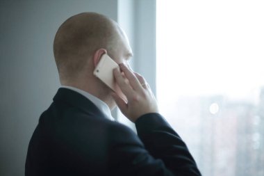 Ofis pencereden dışarı bakarak smartphone ile Dikiz .businessman.