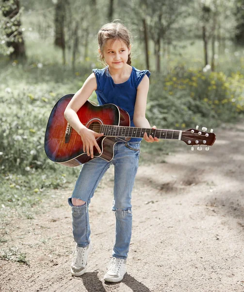 Little girl with guitar standing on the path in the city Park — Stock Photo, Image