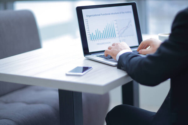 бизнесмен работает на ноутбуке с финансовыми документами
