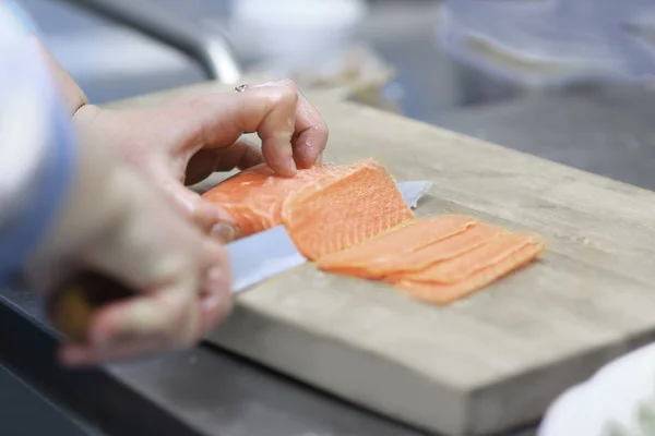 Nahaufnahme. Koch schneidet Fisch für Sushi — Stockfoto