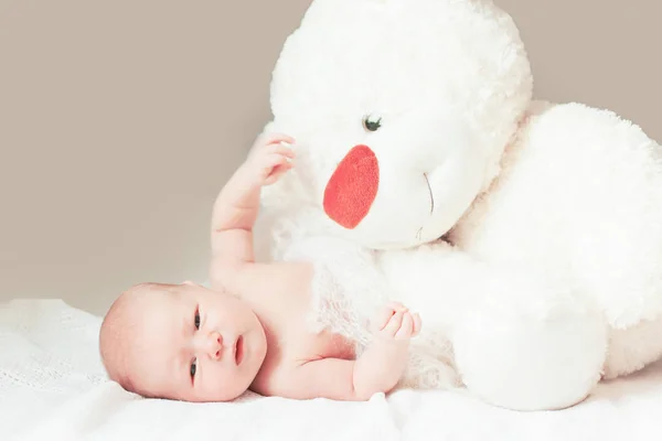 Vrij pasgeboren babymeisje met een groot zacht stuk speelgoed op de deken liggen. — Stockfoto