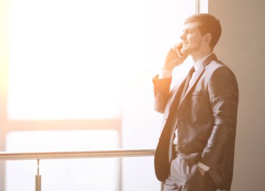 Smartphone cep telefonu ile bir ofis pencere yanında dururken konuşmaya up.businessman kapatın